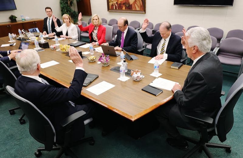 Cinq membres du Conseil exécutif missionnaire sont assis à une table et lèvent la main pour soutenir une proposition lors d'une réunion du Conseil exécutif missionnaire à l'immeuble des bureaux de l'Église à Salt Lake City, le mercredi 26 mai 2021.