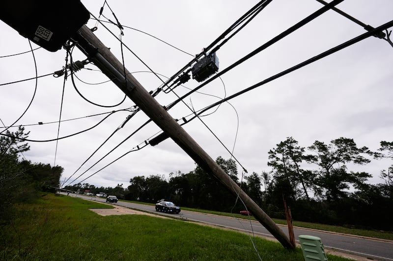 Des patrouilleurs de la police d'État passent devant des lignes électriques tombées après le passage de l'ouragan Isaias à Milton, en Floride, le samedi 10 octobre 2026.