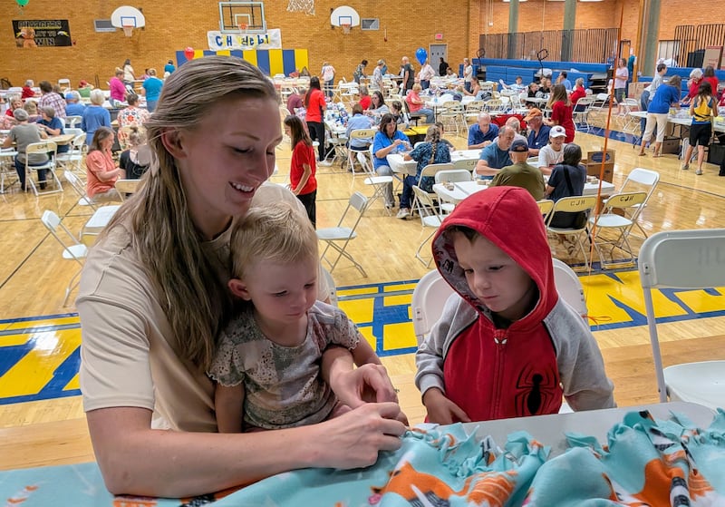 Tawnya Turner montre à ses enfants comment nouer une couverture en polaire dans le cadre d'un événement de la Journée nationale du service et du souvenir à Centerville (Utah), le samedi 12 septembre 2026.