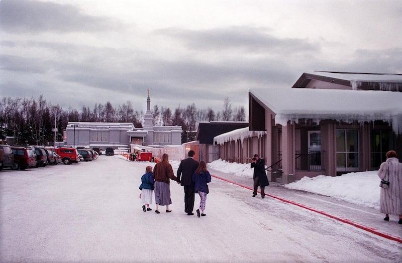 Avec le temple d'Anchorage (Alaska) en arrière-plan et le lieu de culte adjacent à droite, une famille est photographiée arrivant pour la consécration du temple le 9 janvier 1999, à Anchorage (Alaska).