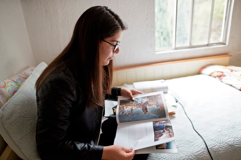 Une femme est assise sur un lit et étudie le manuel "Viens et suis-moi".