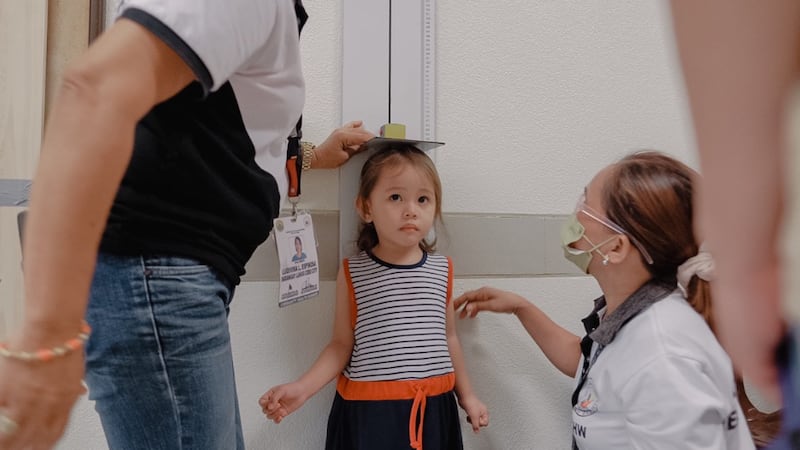 Des travailleurs de la santé mesurent la taille d'un enfant lors d'un dépistage à Cebu City, aux Philippines, le 16 août 2022.