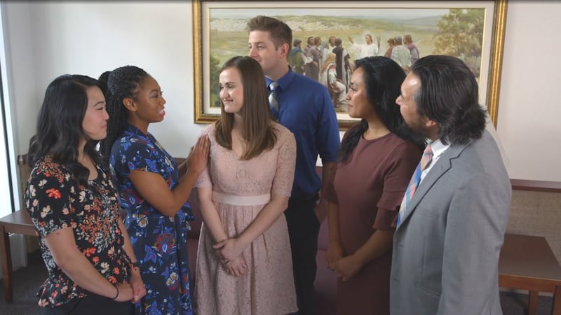 Six personnes se saluent dans le foyer d'un bâtiment de l'Église avant la réunion de sainte-cène.