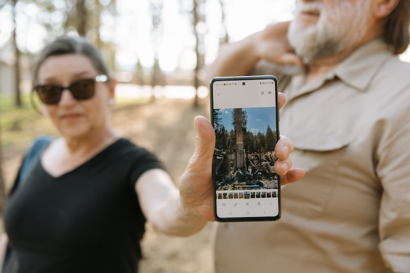 Cherie Tolman montre une photo de ce qu'il reste de leur maison après sa destruction par les feux de forêt de Spokane au début du mois d'août, à Spokane, dans l'État de Washington, le samedi 22 août 2026.