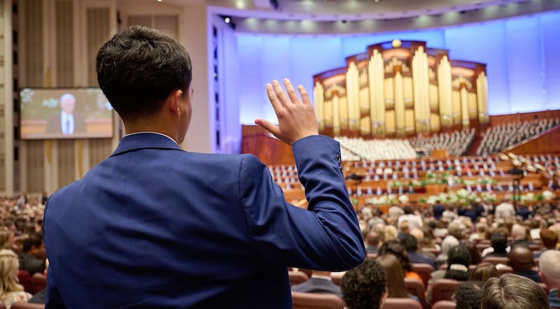Un jeune homme est photographié pendant qu’il lève la main durant la conférence générale au Centre de conférences de Salt Lake City (Utah).